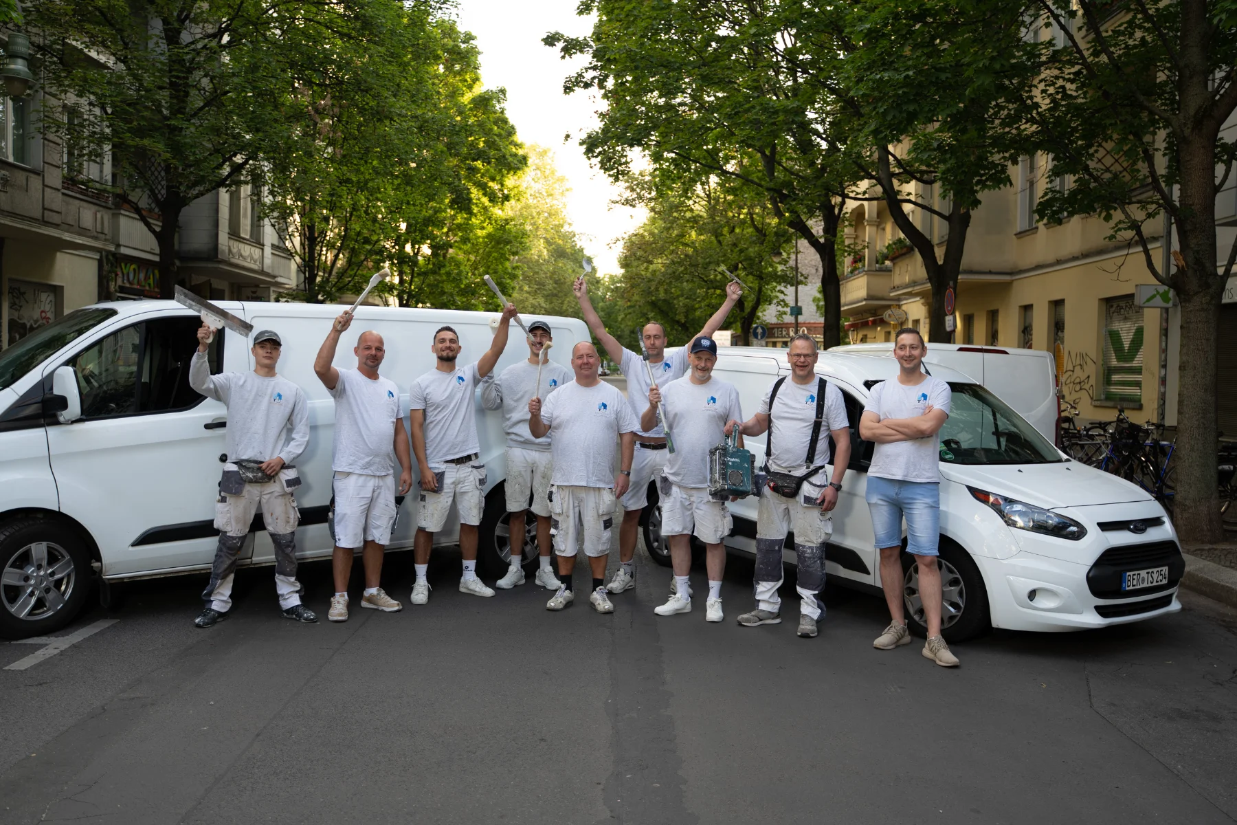 Das Team von Malerbetrieb Sens vor den Firmenfahrzeugen in Berlin